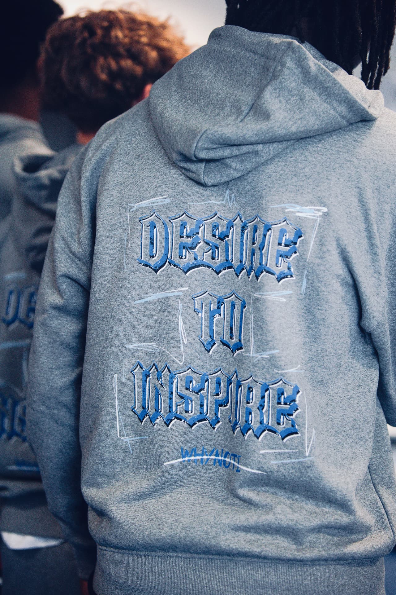 The back of a grey Why Not I hoodie reading Desire to Inspire at the 2025 Workout
