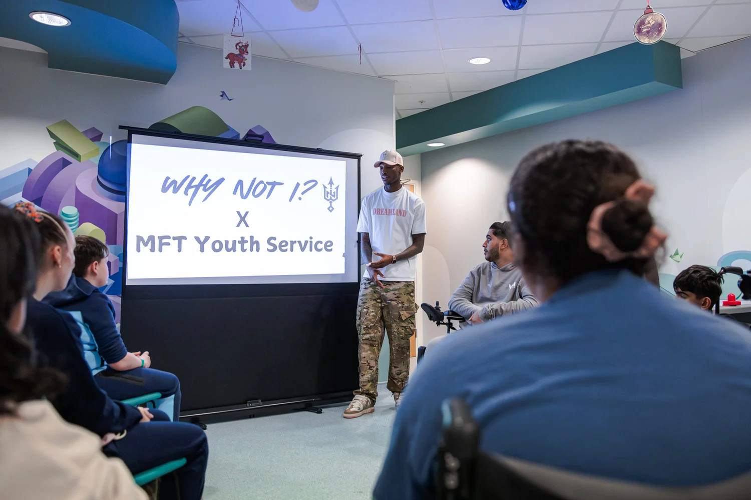 A Why Not I team member speaking with young people in the hospital youth service room