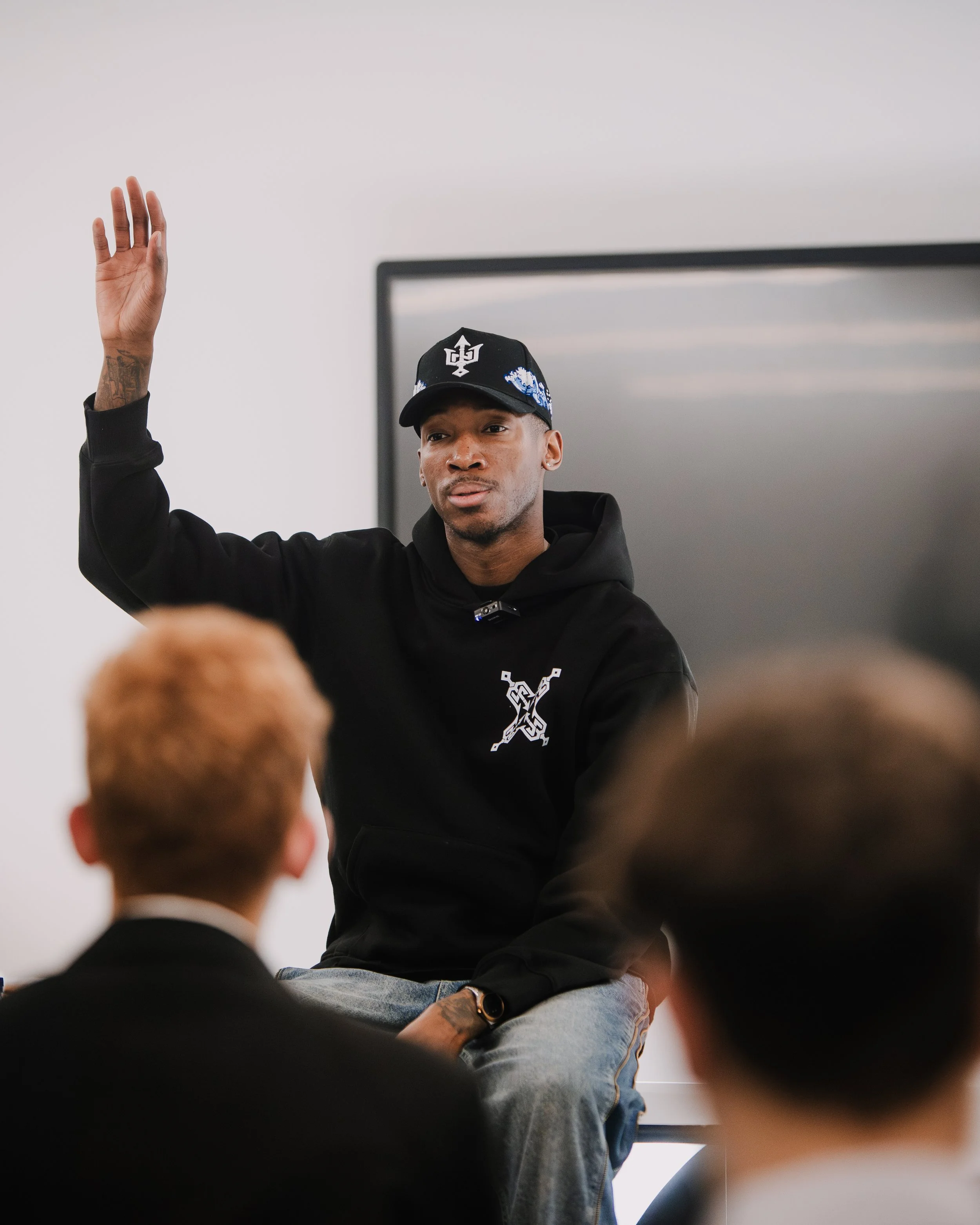 Kofi Josephs raising his hand while speaking to a small student group