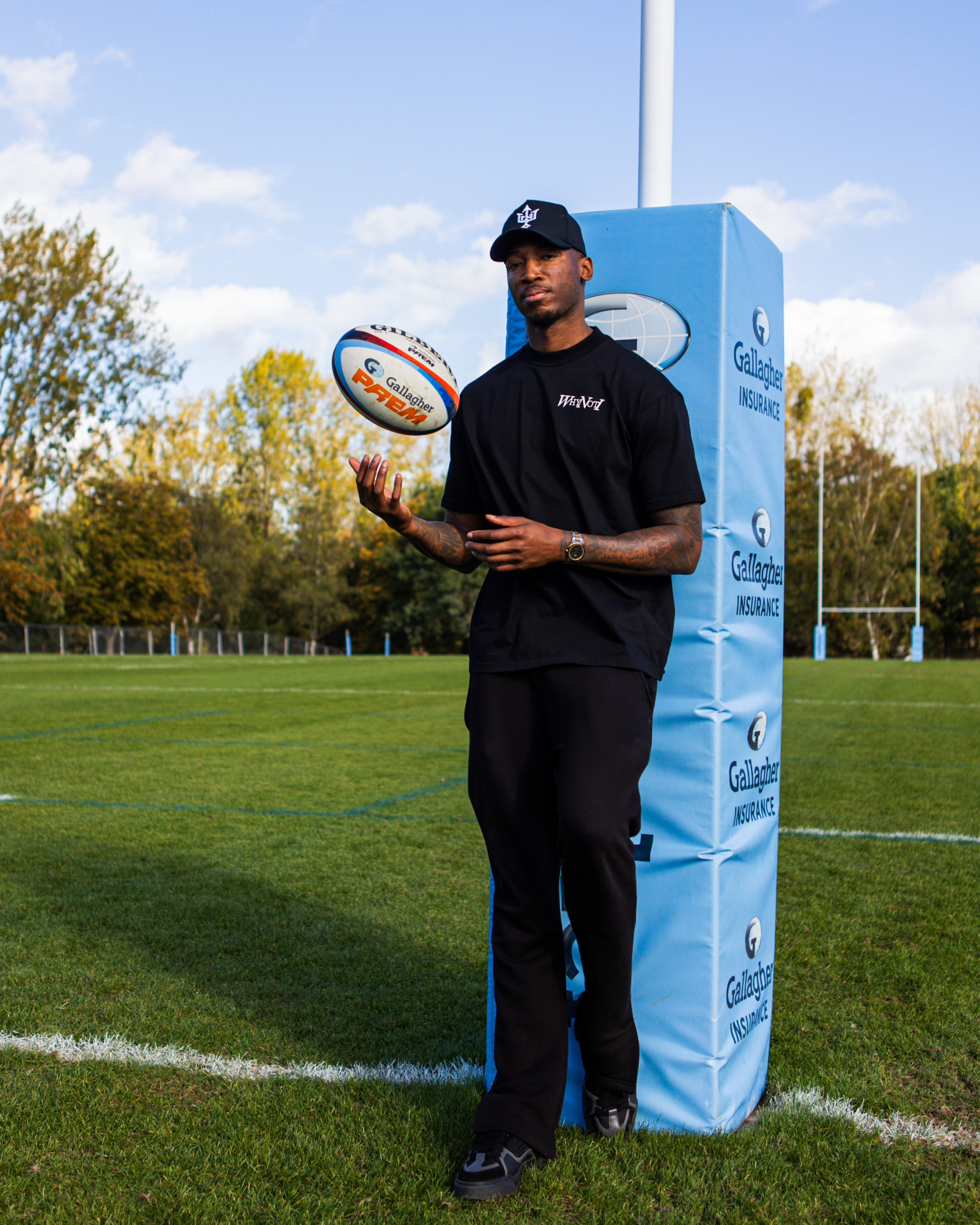 Kofi Josephs balancing a rugby ball on his hand beside a goalpost on the Harlequins pitch