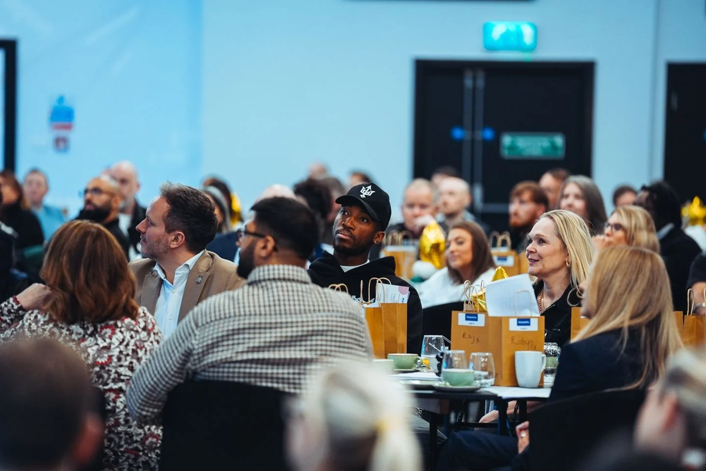 Conference attendees listening from tables in the event room