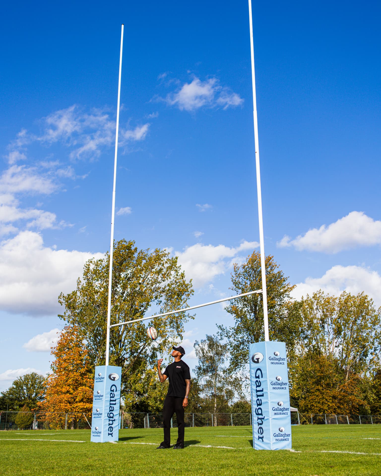 Kofi Josephs under the posts on the Harlequins pitch with a rugby ball in the air
