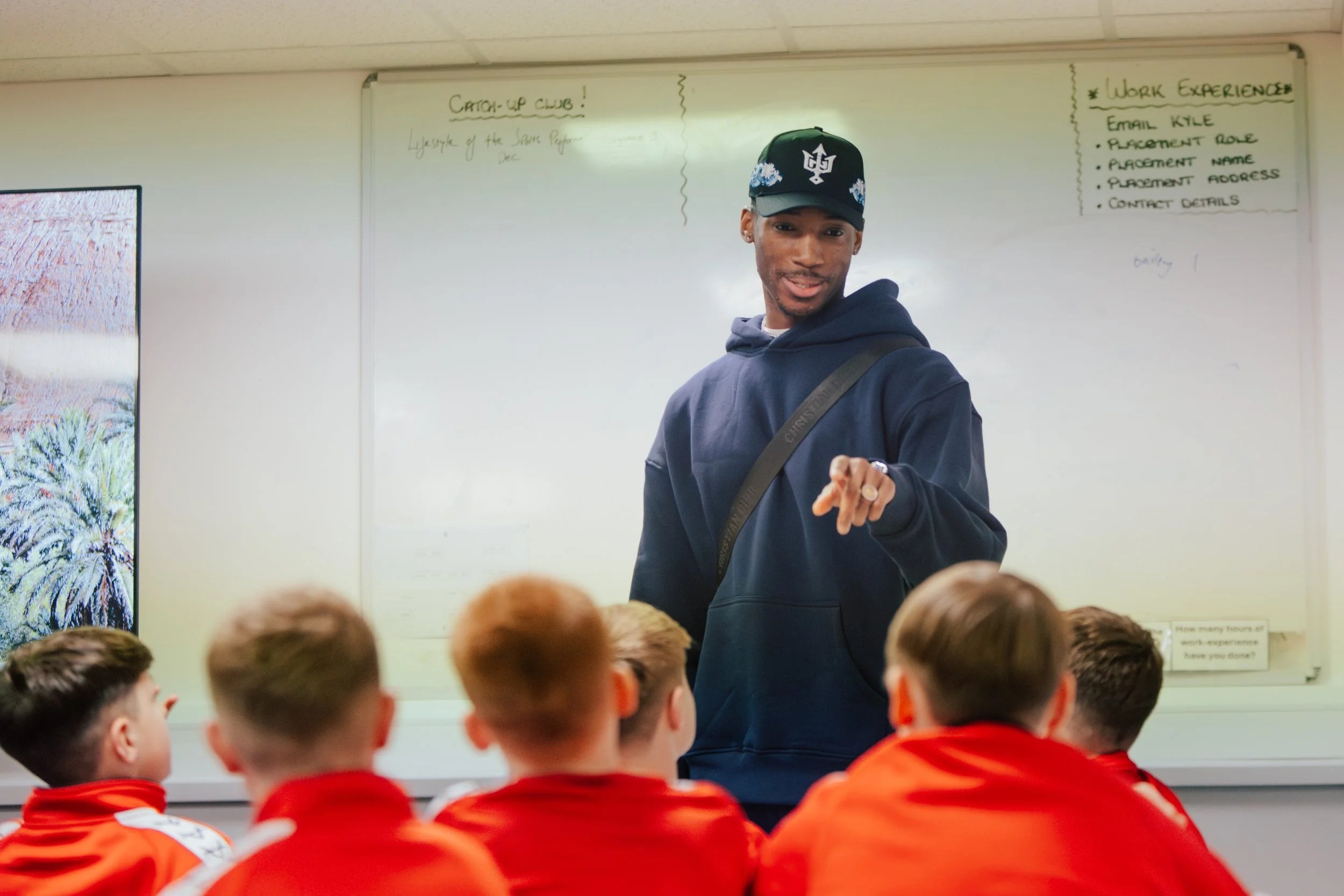 Kofi Josephs in conversation with Doncaster Rovers Academy players in a classroom