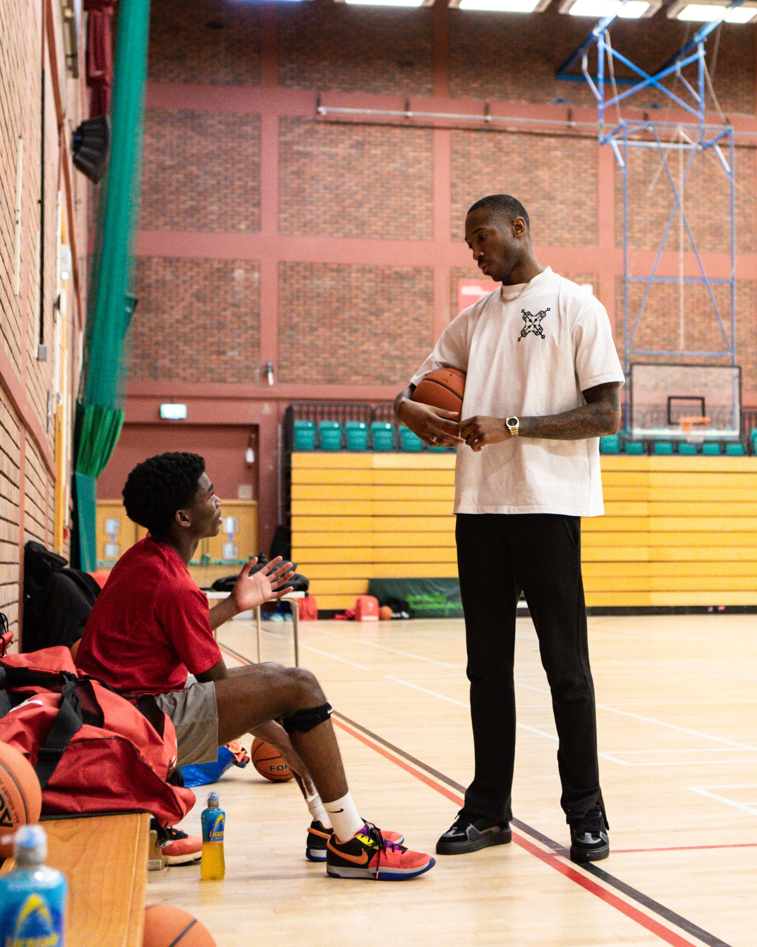 Kofi Josephs standing with Basketball Wales players in the sports hall