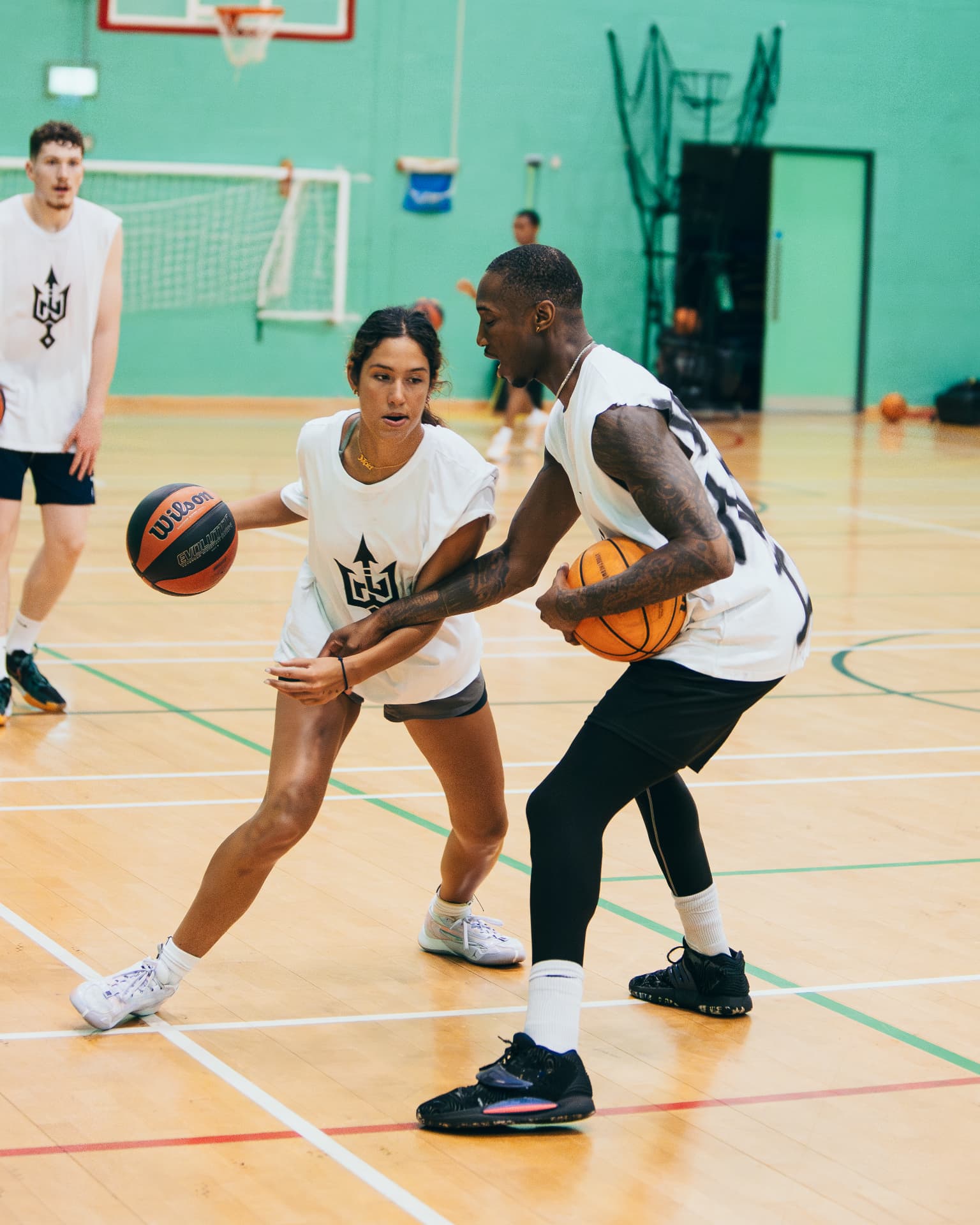 A participant drives past a defender during a one-to-one basketball drill at the 2024 Workout